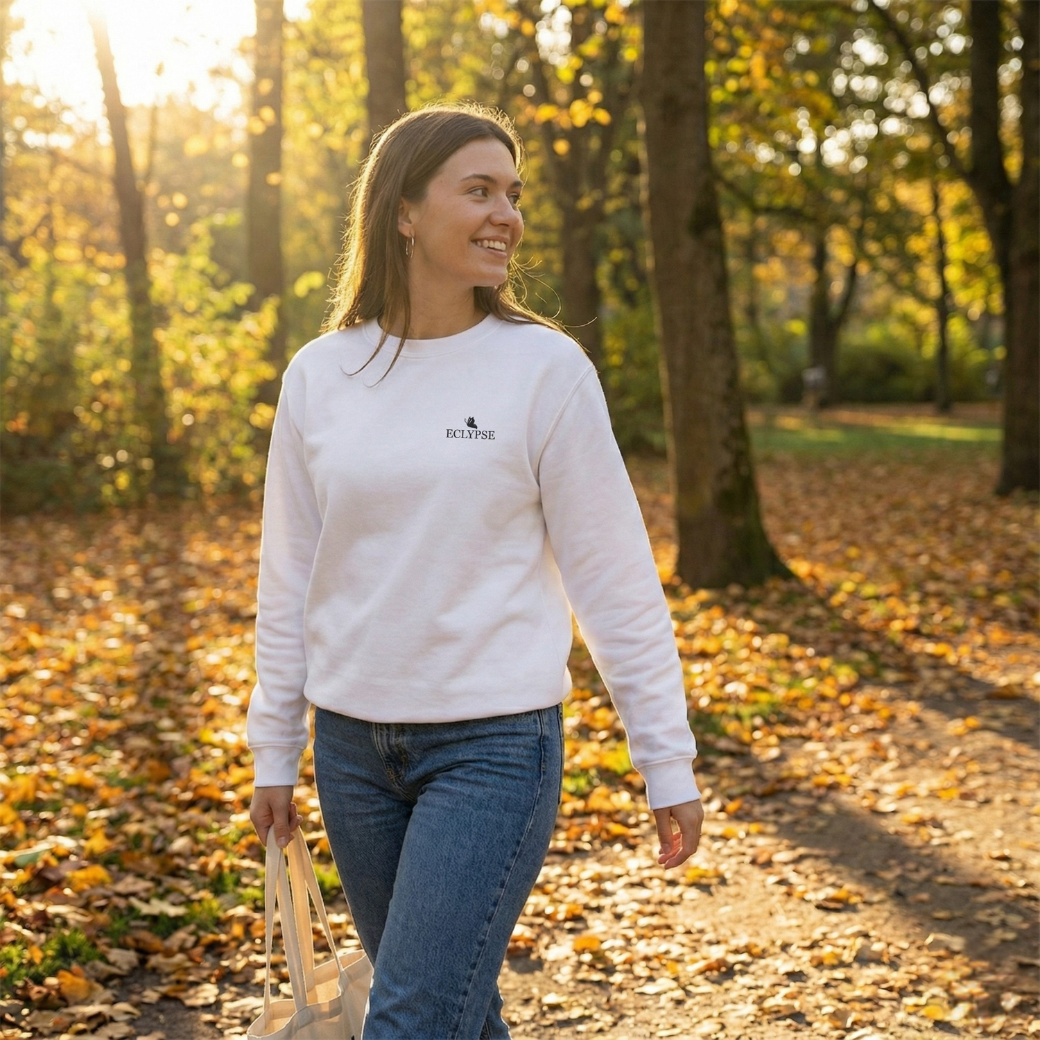 Lachende vrouw wandelt door een herfstbos in een witte Eclypse sweater